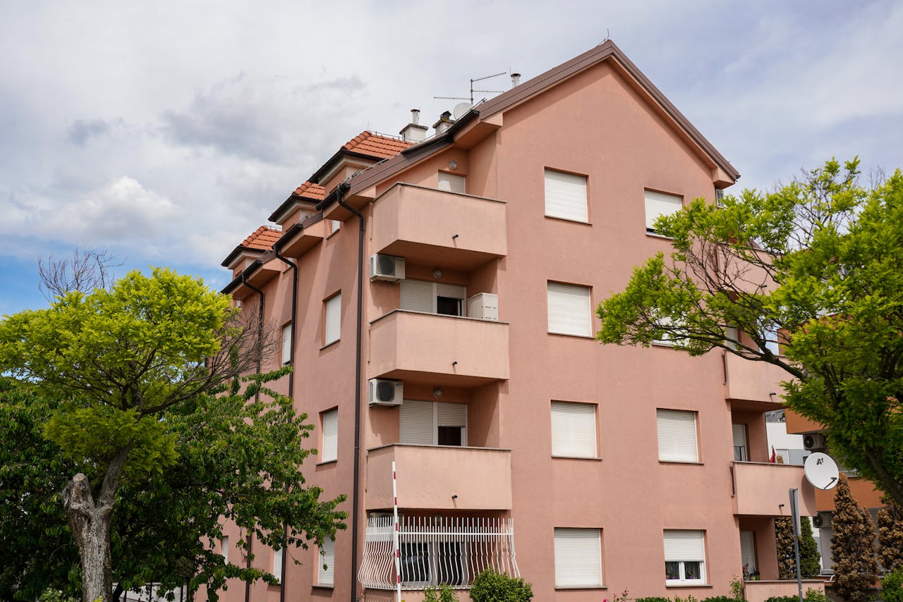 View of a pink residential building surrounded by lush greenery in Zagreb, Croatia.